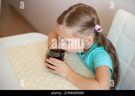 Happy little girl drinking soda from glass Stock Photo