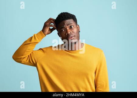 Confused black guy touching his head, blue background Stock Photo