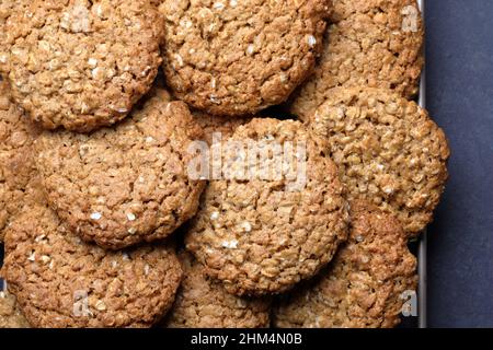 Homemade crunchy oat biscuits cookies cooling on a wire rack on a dark background Stock Photo