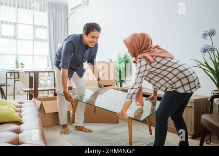 Attractive family of woman with hijab and man relocation furniture in new home Stock Photo