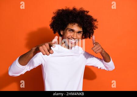 Photo of pretty cool guy dressed white shirt pointing two fingers you isolated orange color background Stock Photo