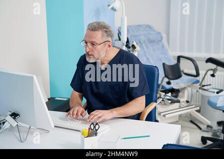 Physician working on desktop computer in his office Stock Photo