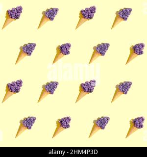 Seamless pattern with waffle cones on a yellow background with hard shadows. Summer pattern with lilac flowers in ice cream cones on a lemon color bac Stock Photo