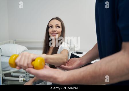 Disabled woman performing strength training exercise with physiotherapist Stock Photo