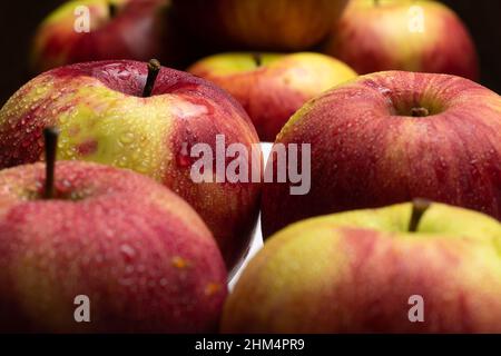 Red-yellow apples with drops close-up on a white plate. Fruit on a plate. Apples on a dark background. Macro Stock Photo