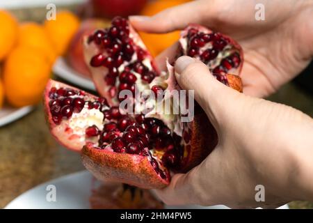 Close-up of female hands holding an open ripe juicy pomegranate Stock Photo