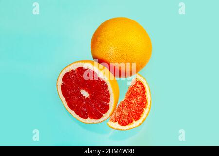 Whole and sliced juicy grapefruits on a light blue background. Food background. Stock Photo