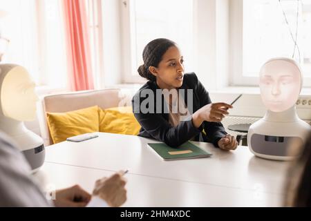 Businesswoman presenting robot voice assistant during meeting Stock Photo