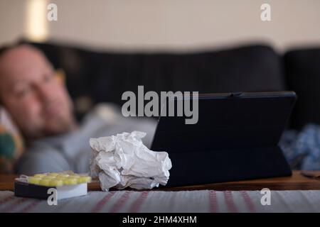 Sick man lying at home and using digital tablet Stock Photo