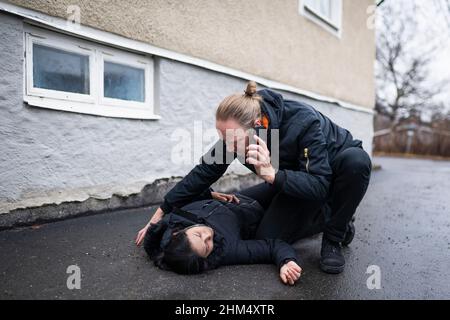 Man calling for ambulance for unconscious woman in medical shock Stock Photo