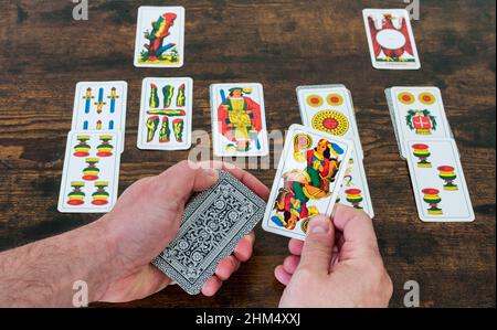 solitaire card game, two hands hold playing cards 'piacentine' and place them on a table Stock Photo