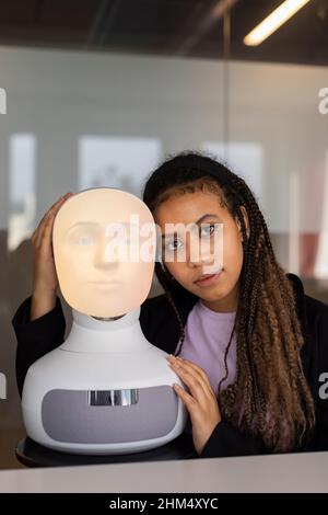 Portrait of young woman with robot voice assistant Stock Photo
