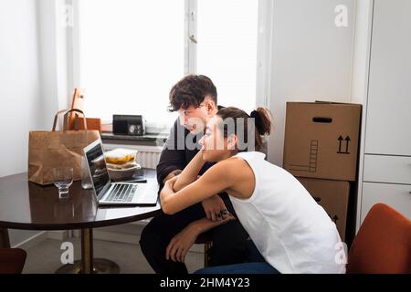 Couple sitting at table and using laptop Stock Photo