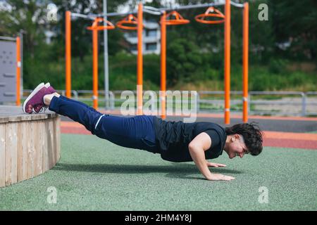 Young woman doing push-ups at outdoor gym Stock Photo