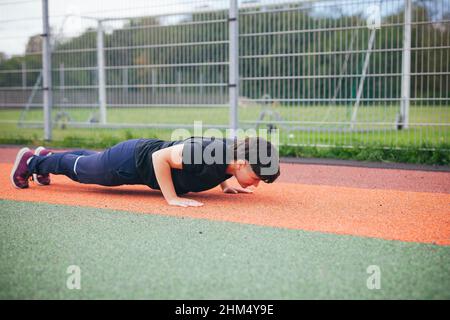 Young woman doing push-ups at outdoor gym Stock Photo