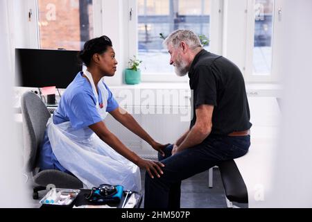 Female doctor comforting senior patient during appointment Stock Photo