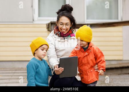 Woman with children at playground using digital tablet Stock Photo