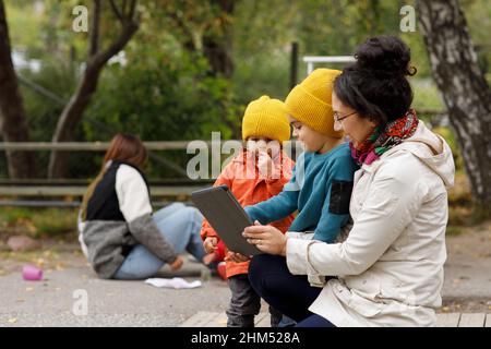 Woman with children at playground using digital tablet Stock Photo