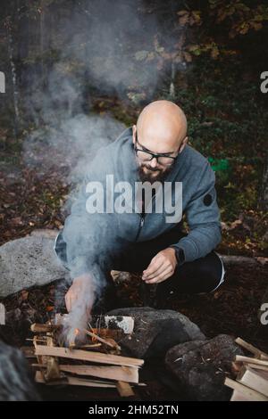 Man making campfire in forest Stock Photo