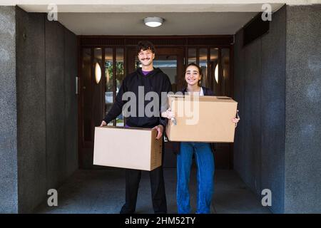 Portrait of smiling couple carrying boxes Stock Photo
