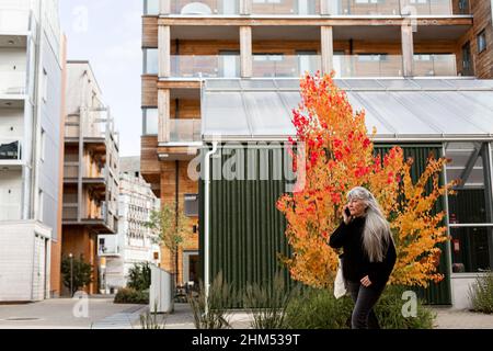 Senior woman talking on cell phone in front of building Stock Photo