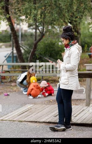 Woman at playground using digital tablet Stock Photo