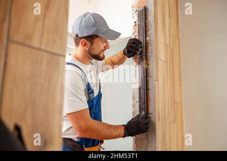 Craftsman, male worker in uniform using bubble level while measuring the wall indoors Stock Photo