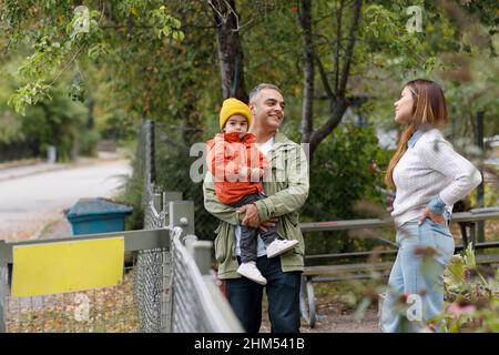 Parents talking together, father carrying child Stock Photo