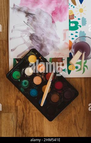 Abstract painting, paint box, and brushes on table Stock Photo