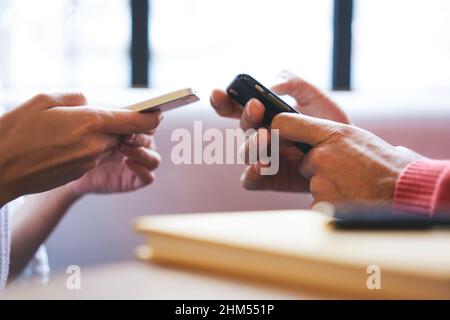 Crop male and female browsing modern smartphones together Stock Photo