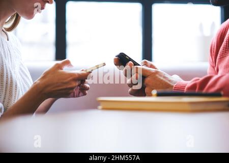 Crop coworkers surfing smartphones while sitting at table Stock Photo