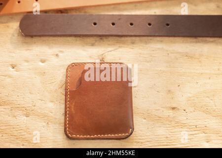 High angle view of leather belt and wallet on wooden table in workshop Stock Photo