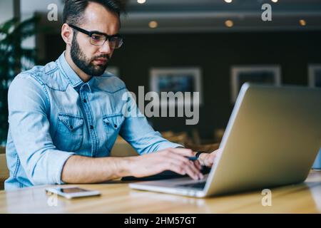 Focused male freelancer using laptop during workday Stock Photo