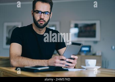 Serious freelancer using tablet in cafe Stock Photo