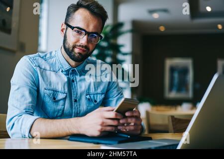Positive man using smartphone in cafe Stock Photo