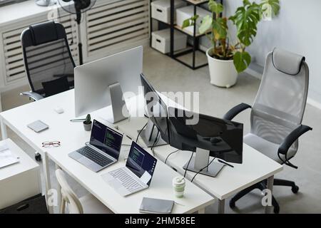 Part of contemporary open space bureau of diversity programming with computer monitors and two laptops on desks Stock Photo