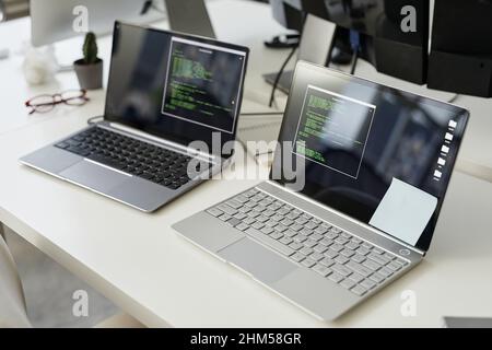 Two laptop computers with coded data and notepapers on screens standing on workplace of modern diversity programmer in office Stock Photo
