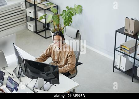 Young serious male diversity programmer looking attentively at computer screen while working over development of new program Stock Photo