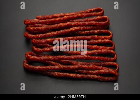 Cabanossi, dry sausage isolated on a black background. Stock Photo