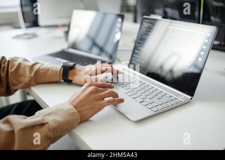 Hands of young contemporary program developer typing on laptop keyboard while sitting by desk in office or bureau Stock Photo