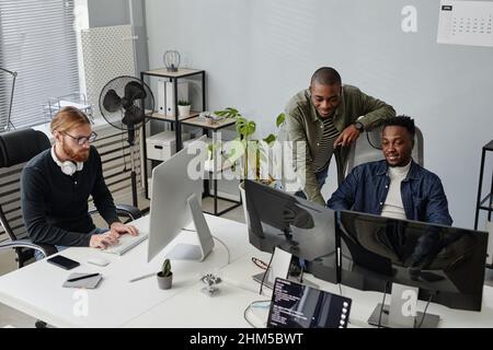 Two young African American programmers discussing online data on computer screen at working meeting in openspace bureau Stock Photo