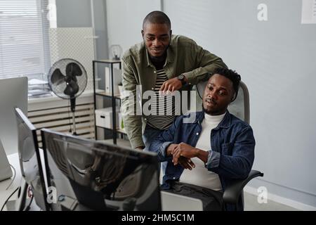 Two young colleagues of African ethnicity discussing working information on computer screen at meeting in openspace bureau Stock Photo