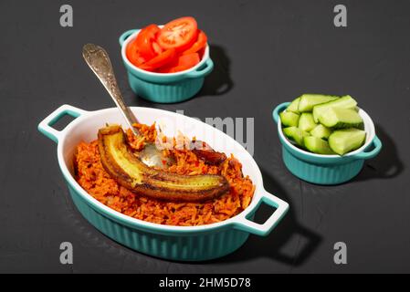 https://l450v.alamy.com/450v/2hm5d78/jollof-rice-with-fried-banana-traditional-nigerian-rice-food-with-tomatoes-onions-and-spices-dark-background-2hm5d78.jpg