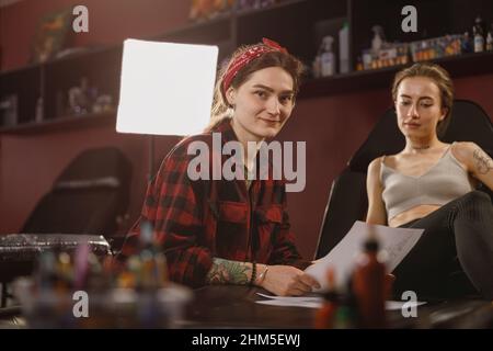 Portrait of smiling female master working in tattoo salon Stock Photo