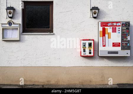 A chewing gum machine and a cigarette vending machine on the wall of a middle class restaurant. Stock Photo