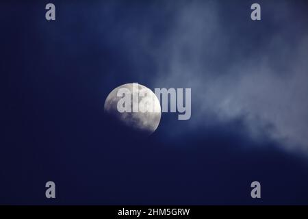 Moon behind dark blue clouds Stock Photo