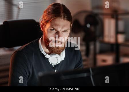 Young contemporary businessman or programmer looking through online data while working late in front of computer in office Stock Photo