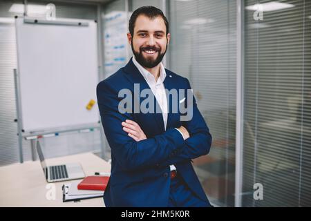 Cheerful businessman in confident pose looking at camera in modern office Stock Photo