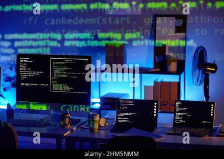 Row of laptops and computer monitor with decoded data on their screens standing on workplace of contemporary diversity programmers Stock Photo