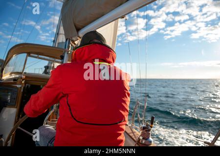 Man steering yacht on the bay of Alicante, Costa Blanca, Spain Stock Photo